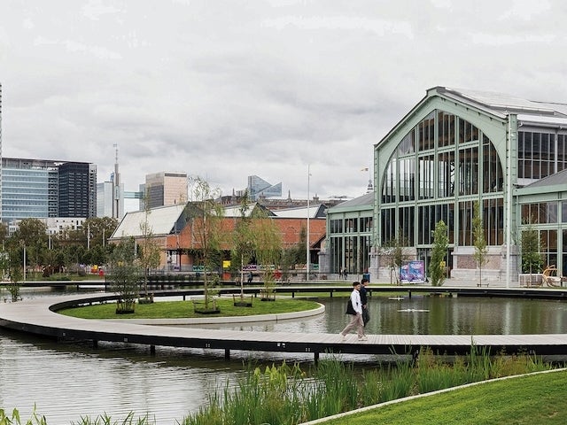 Two people stroll along a walkway over rain-fed ponds at Tour and Taxis, a post-industrial redevelopment project in Brussels
