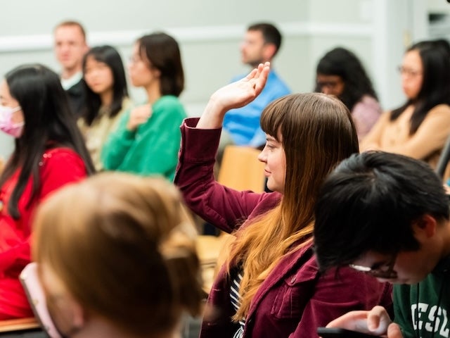 Audience member raises hand during a discussion in a classroom setting