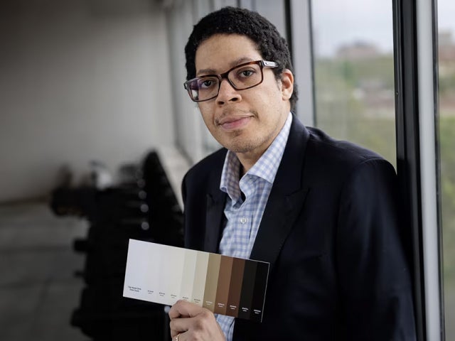 Ellis Monk, Professor of Sociology, shows off the 10-point scale he developed to capture a wide variety of skin tones.