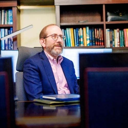 Alan Garber sitting at a desk with a bookshelf behind him