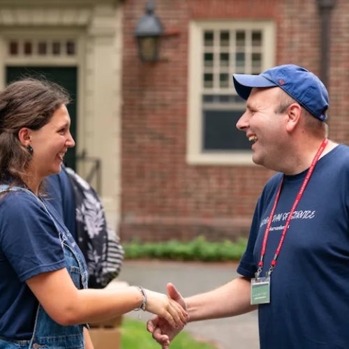  Two people shake hands and smile in Harvard Yard