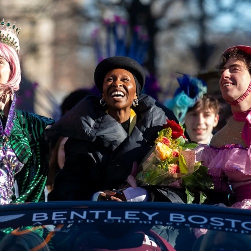 Cynthia Erivo and two Hasty Pudding Theatricals students in costume laugh and look up during the parade