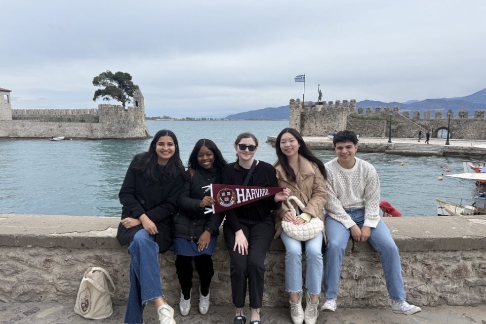 Harvard student posing with a Harvard pennant in Nafpaktos